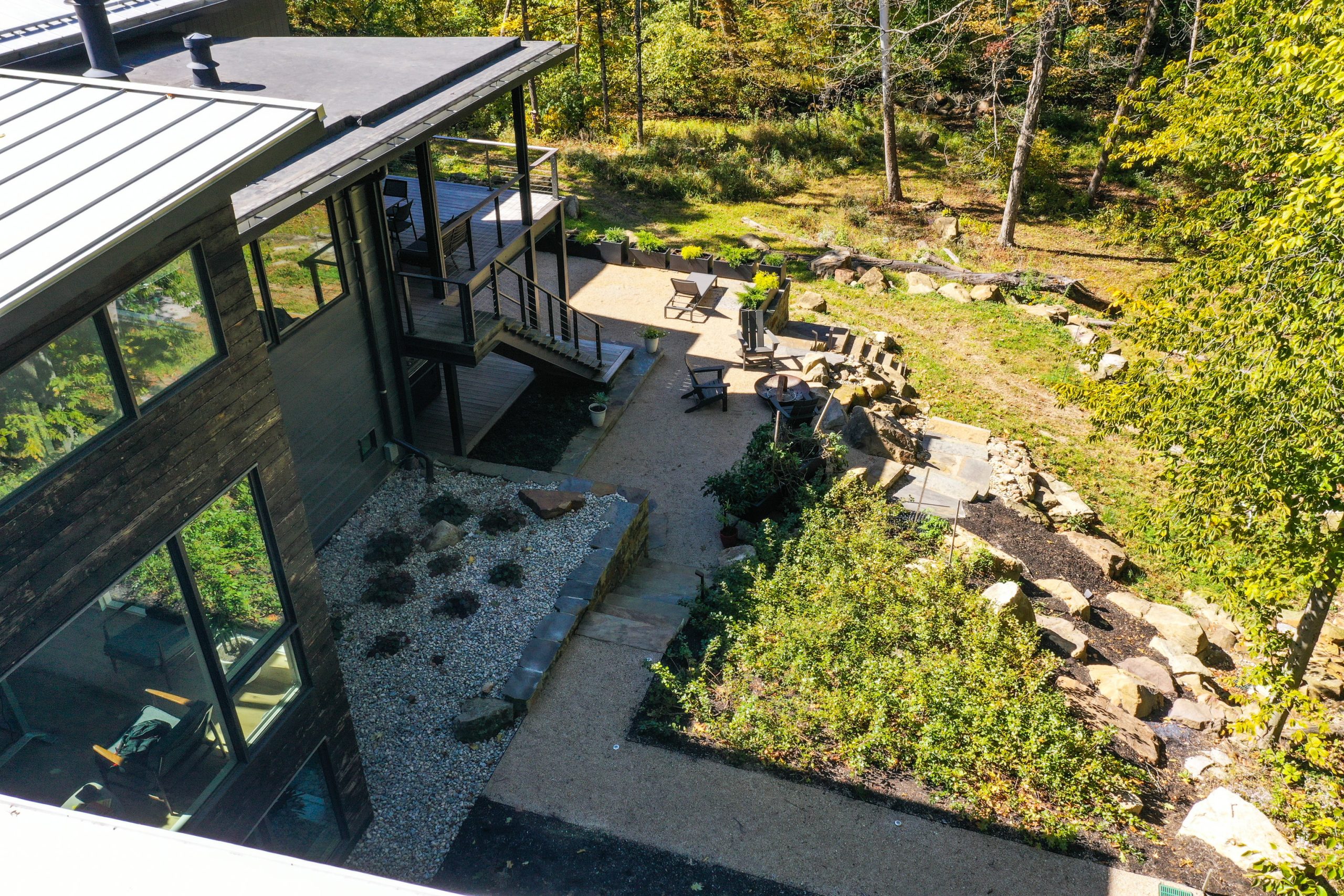 Top view of home backyard surrounded by lawn and forest trees.