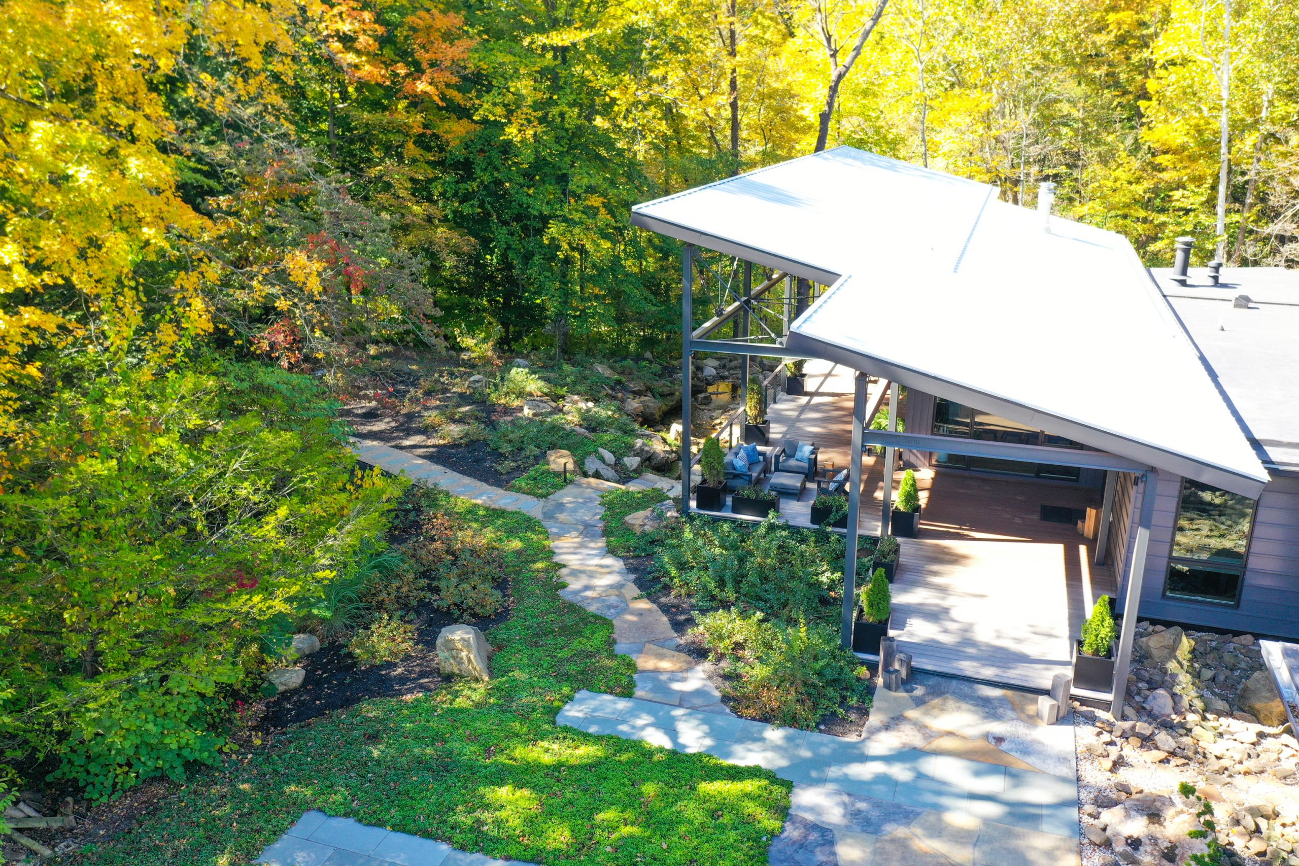 Walkway hardscape surrounded by lawn and colorful forest trees.