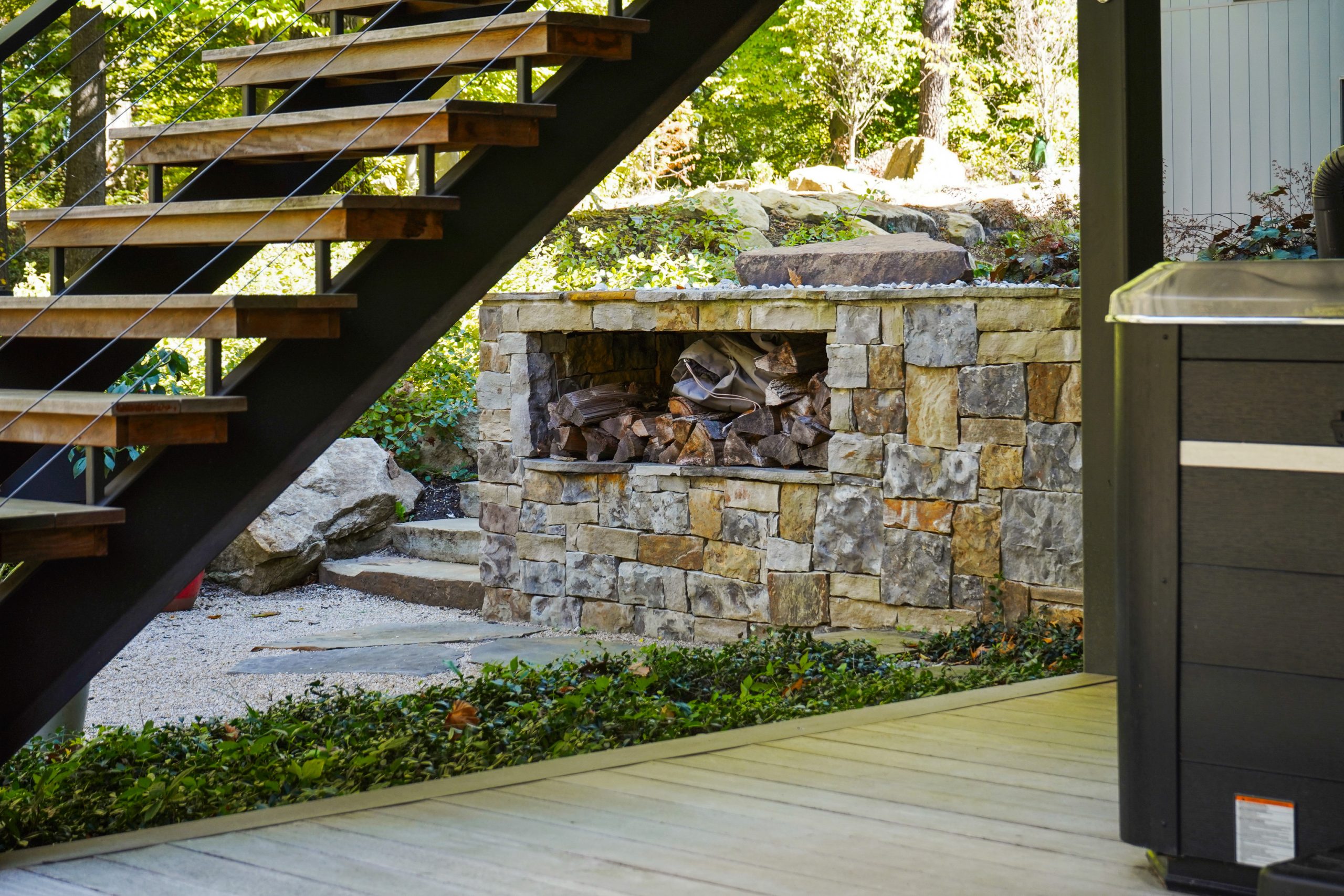 Firewood hardscape under stairs and surrounded by trees