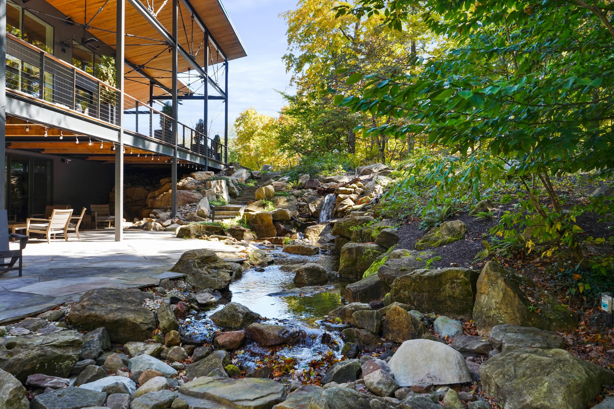 Flowing pondless waterfall of a storey house surrounded by colorful trees.