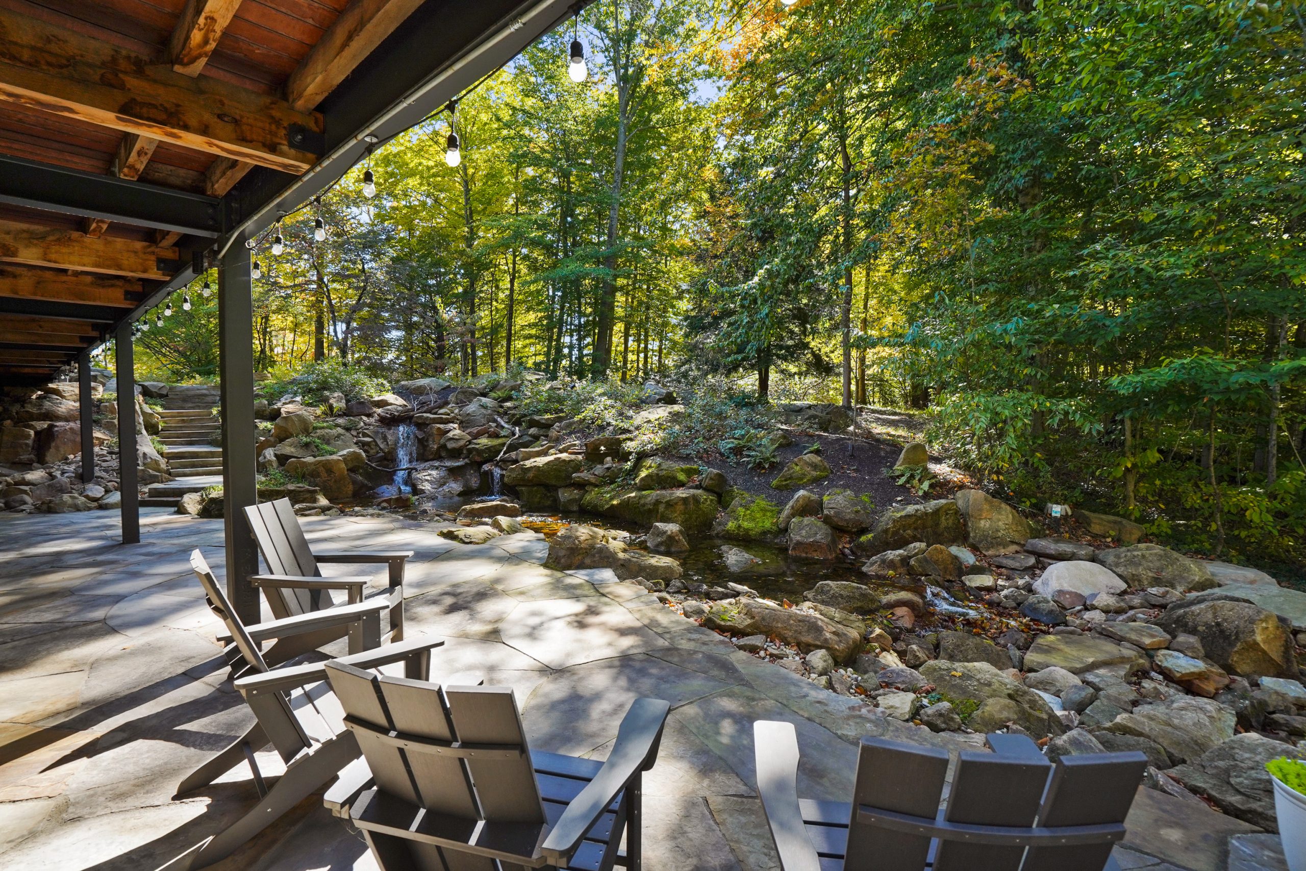 Patio overlooking pondless waterfall and colorful tall trees