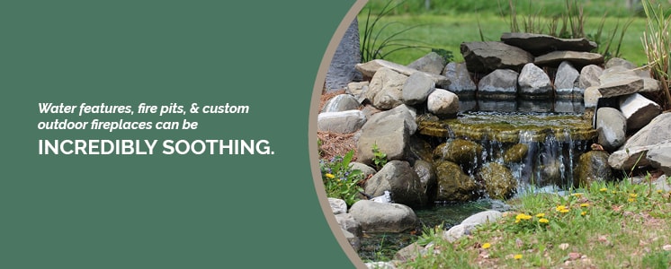 A small natural-looking stone waterfall or fountain cropped into a circle with text set to the left reading "Water features, fit pits, & custom outdoor fireplaces can be incredibly soothing."