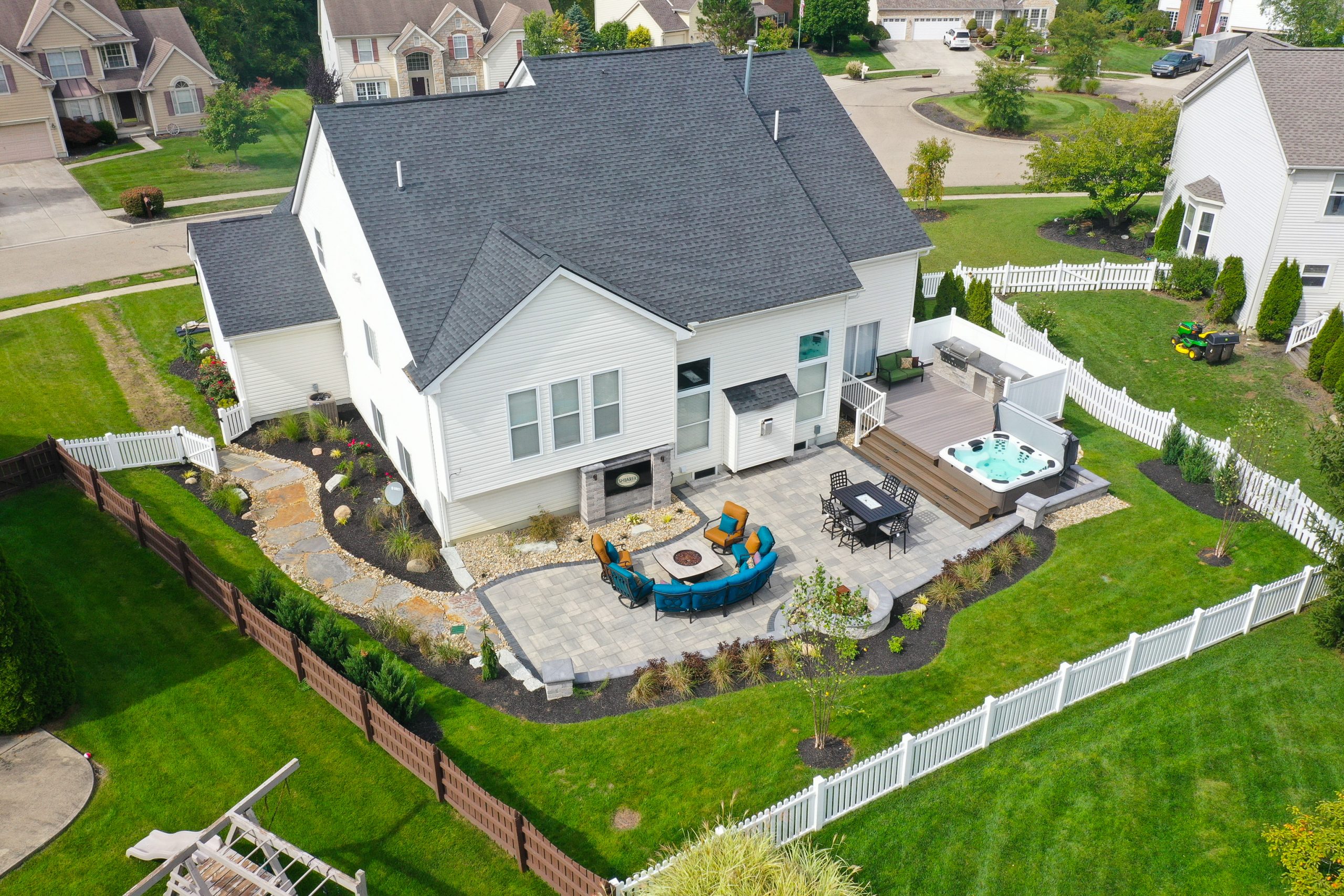 Top view of a community with several homes surrounded by lawns, shrubs and trees.