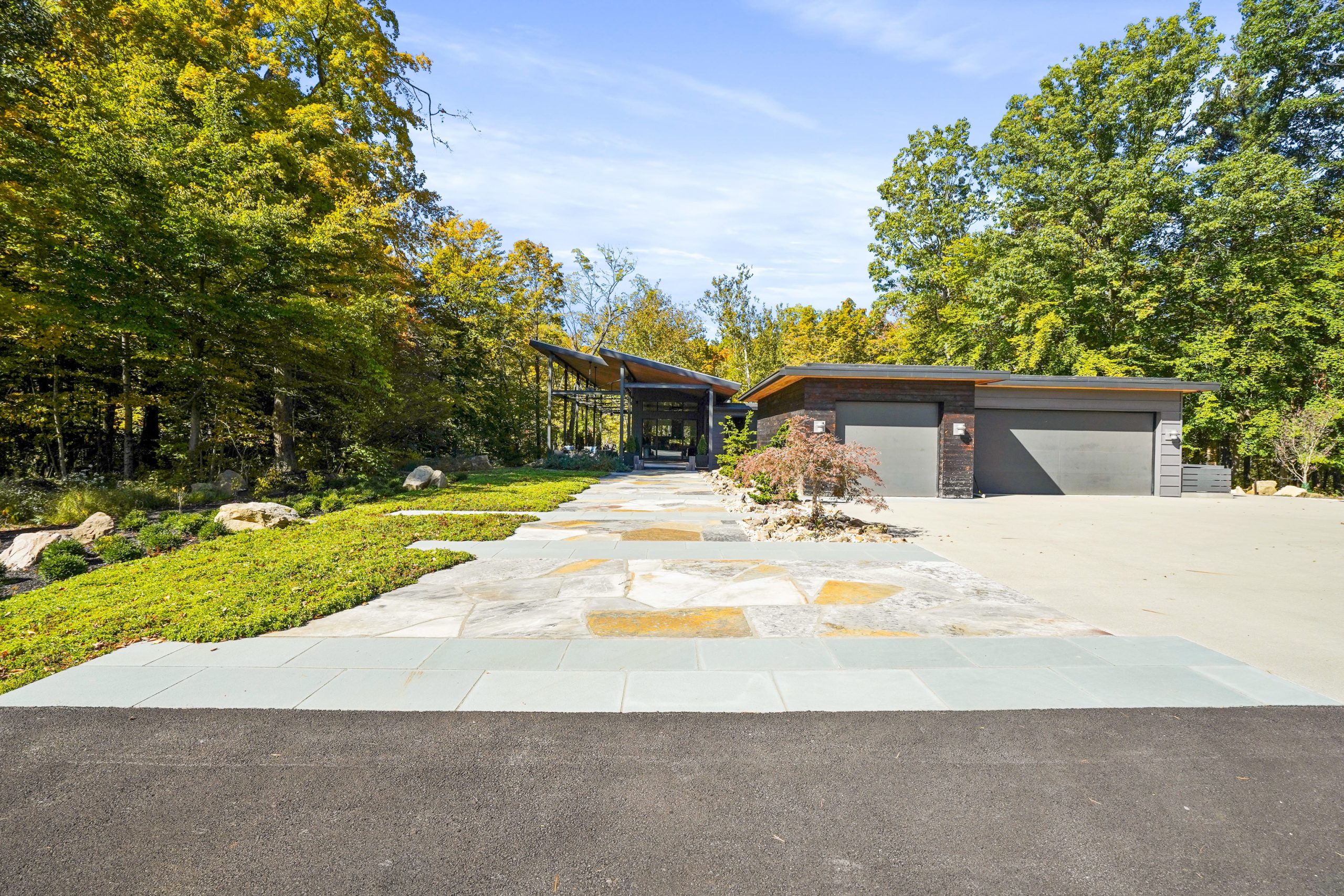 Full view of driveway to a home surrounded by colorful trees.