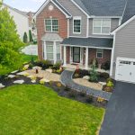 Front view of home showing trees, lawn and walkway between shrubs.