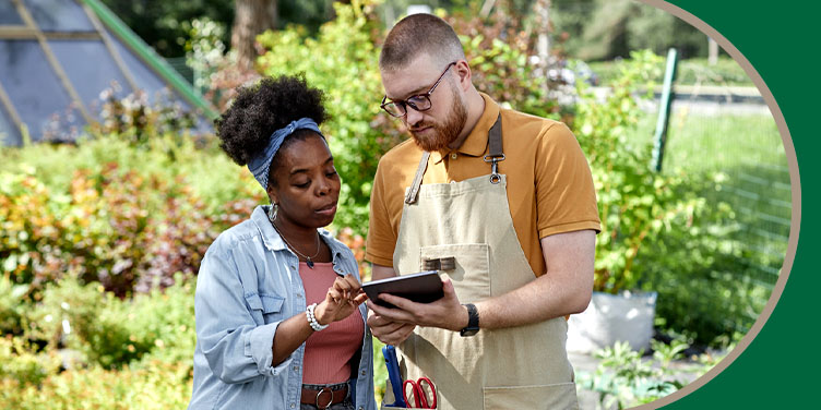 Hardscaping contractor and homeowner reviewing a project plan on a tablet in an outdoor garden.